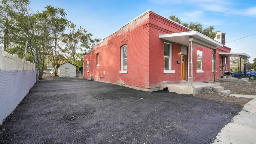 Red brick exterior with white trim windows and a covered front porch featuring a light wood-finish door