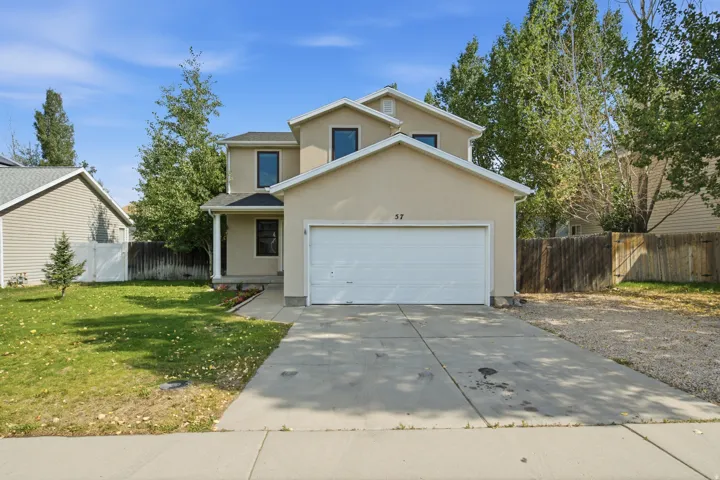 Two-story residence featuring a neutral stucco exterior, a prominent two-car garage, and a covered front entry