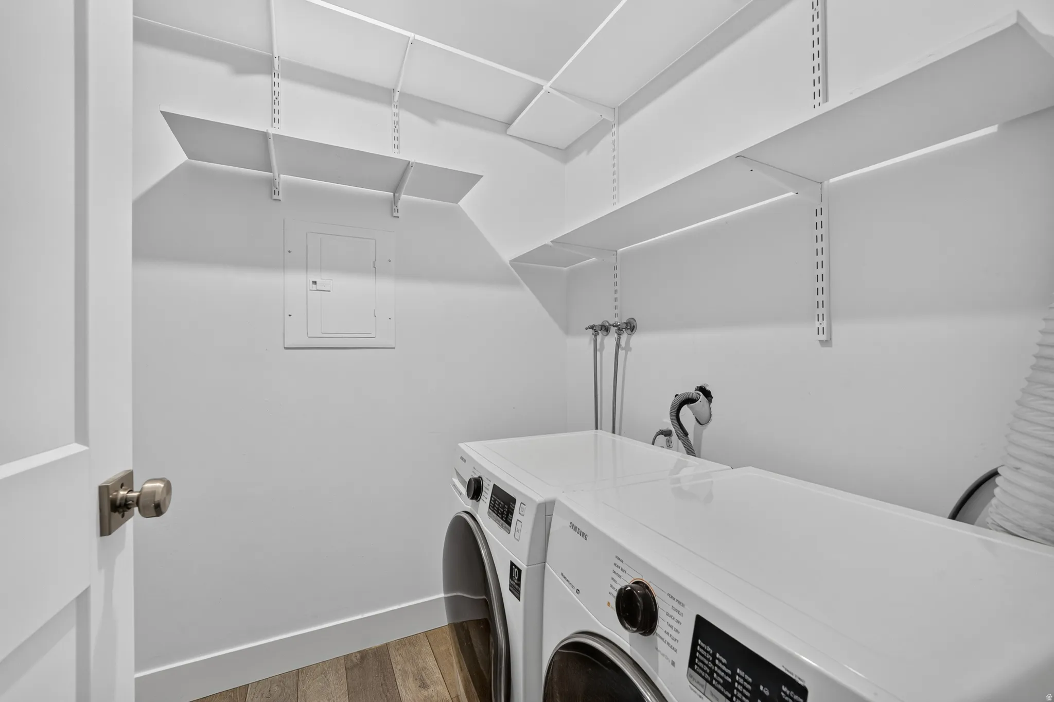 Utility room with wood-finish flooring, white walls, and built-in adjustable shelving