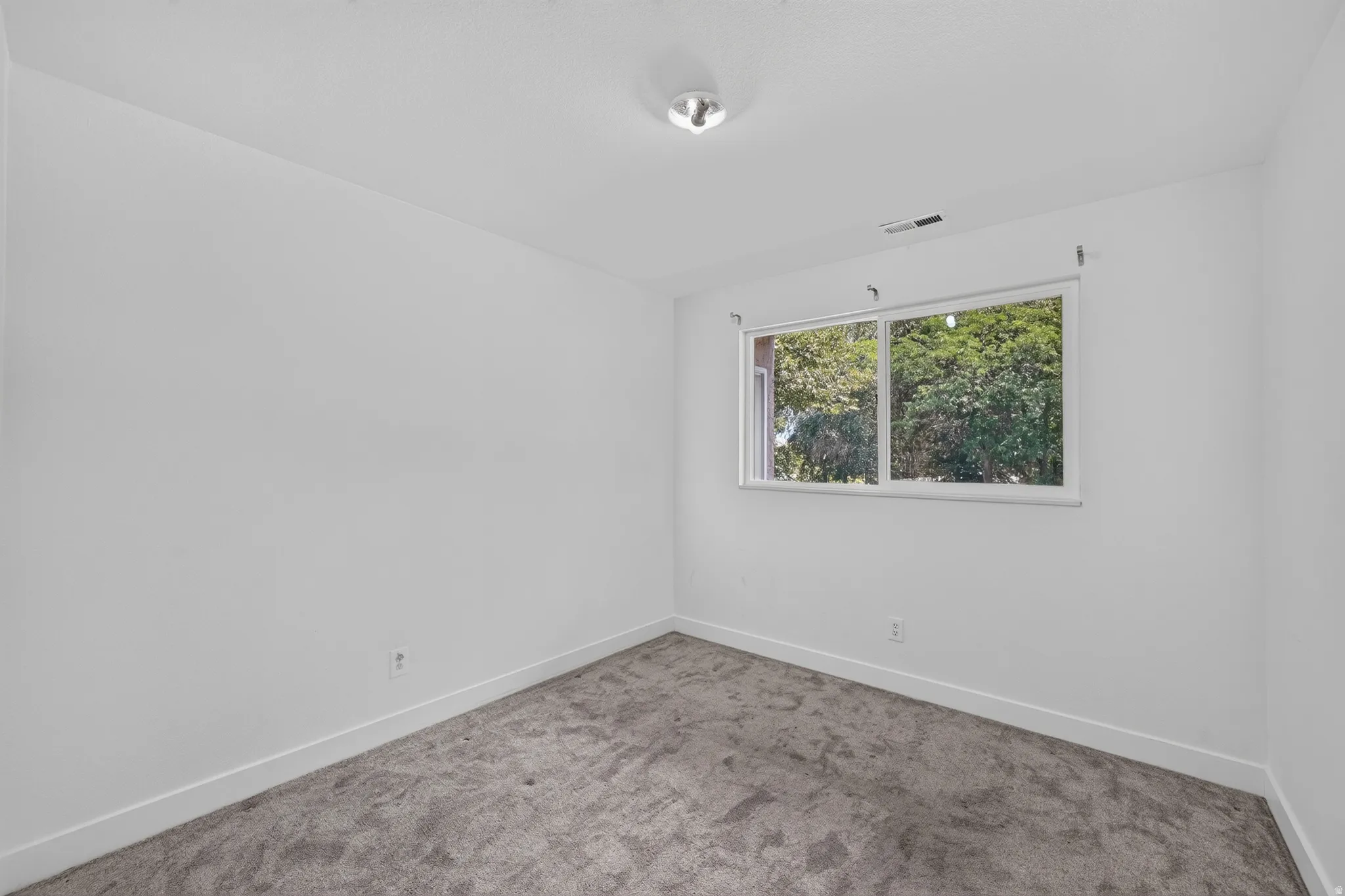 Room featuring light gray carpeting, crisp white walls, and a recessed window