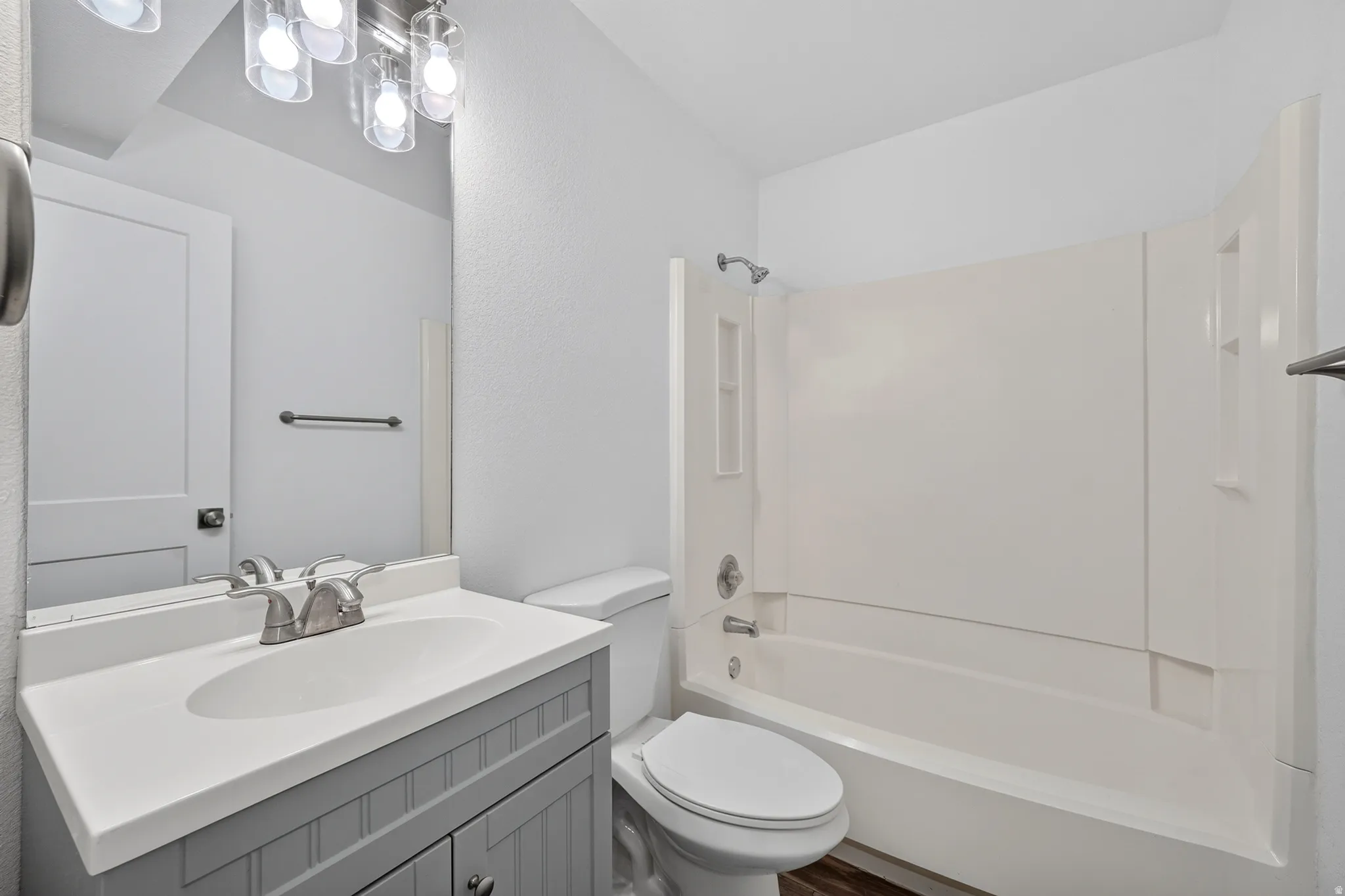 Bathroom featuring a single vanity with a gray paneled cabinet, a white countertop with integrated sink, and a chrome faucet