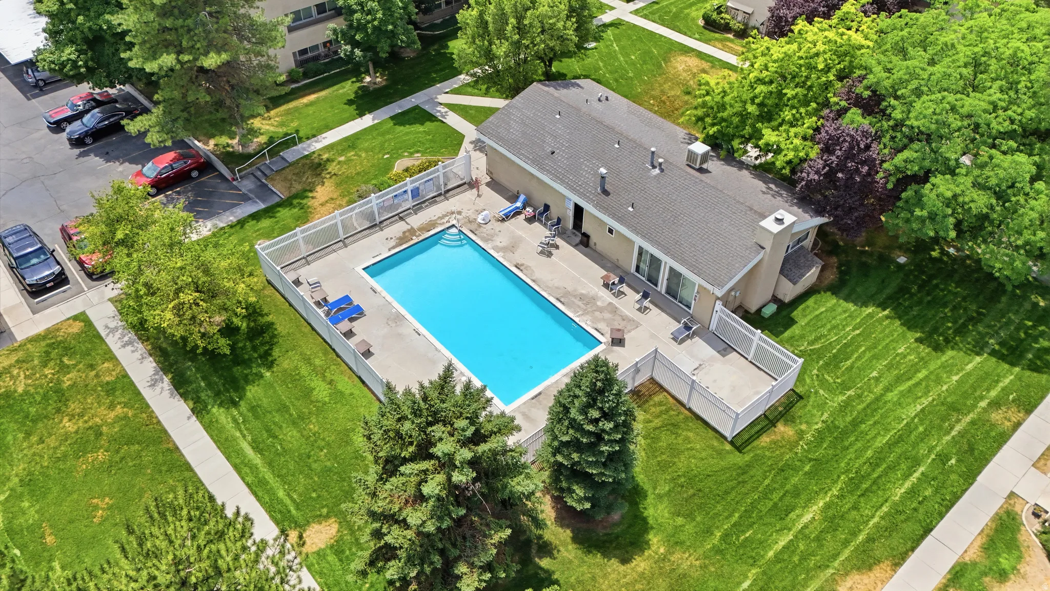 Rectangular swimming pool surrounded by a white privacy fence, featuring an adjacent patio area