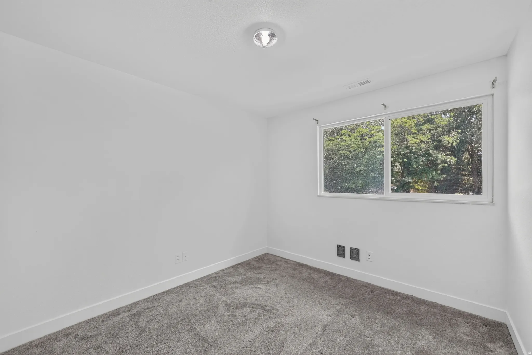 Neutral white walls featuring a single window, recessed lighting, and gray carpet