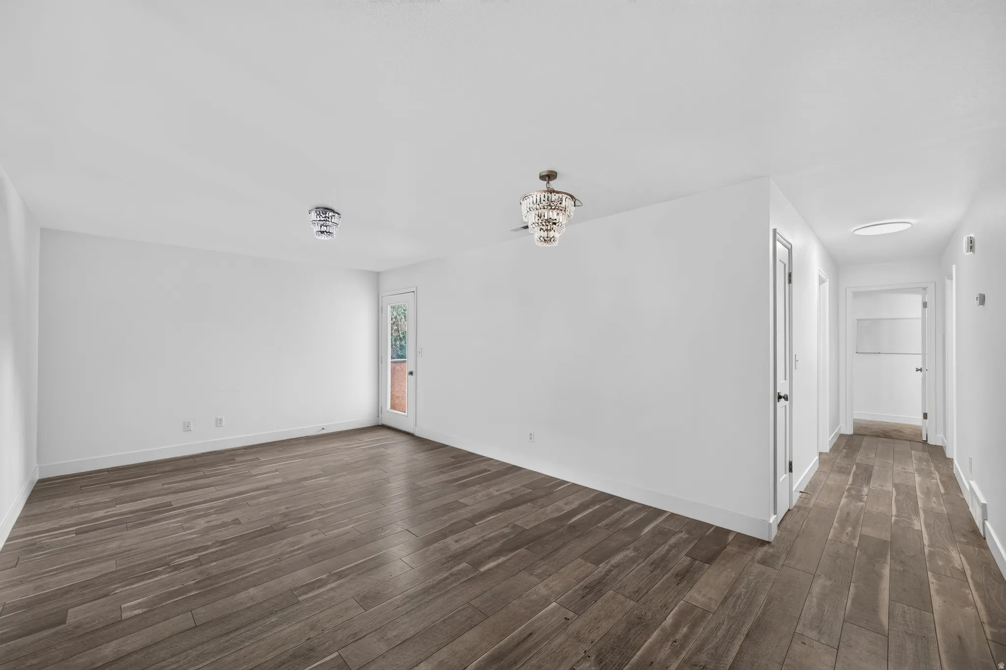 Spacious interior featuring wood-finish flooring, white walls, and a decorative ceiling fan with an integrated light fixture