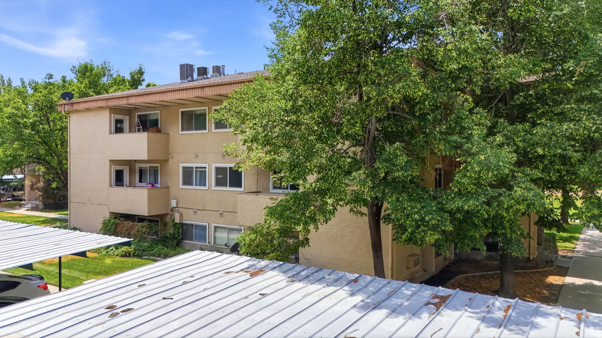 Three-story multi-unit building featuring balconies, numerous windows, and a stucco exterior