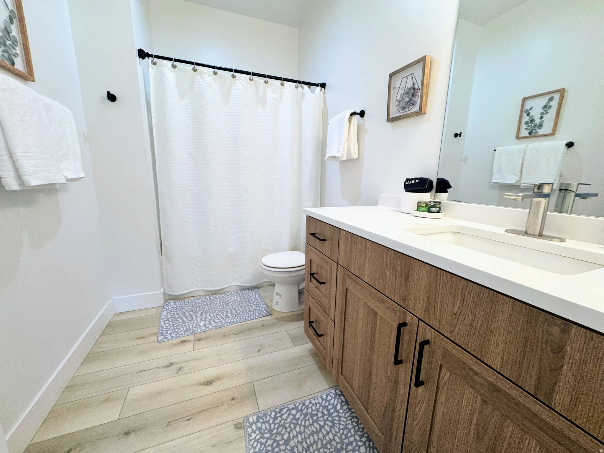 Bathroom featuring a wood-finish vanity with ample storage, a white countertop, and a rectangular undermount sink with a brushed nickel faucet