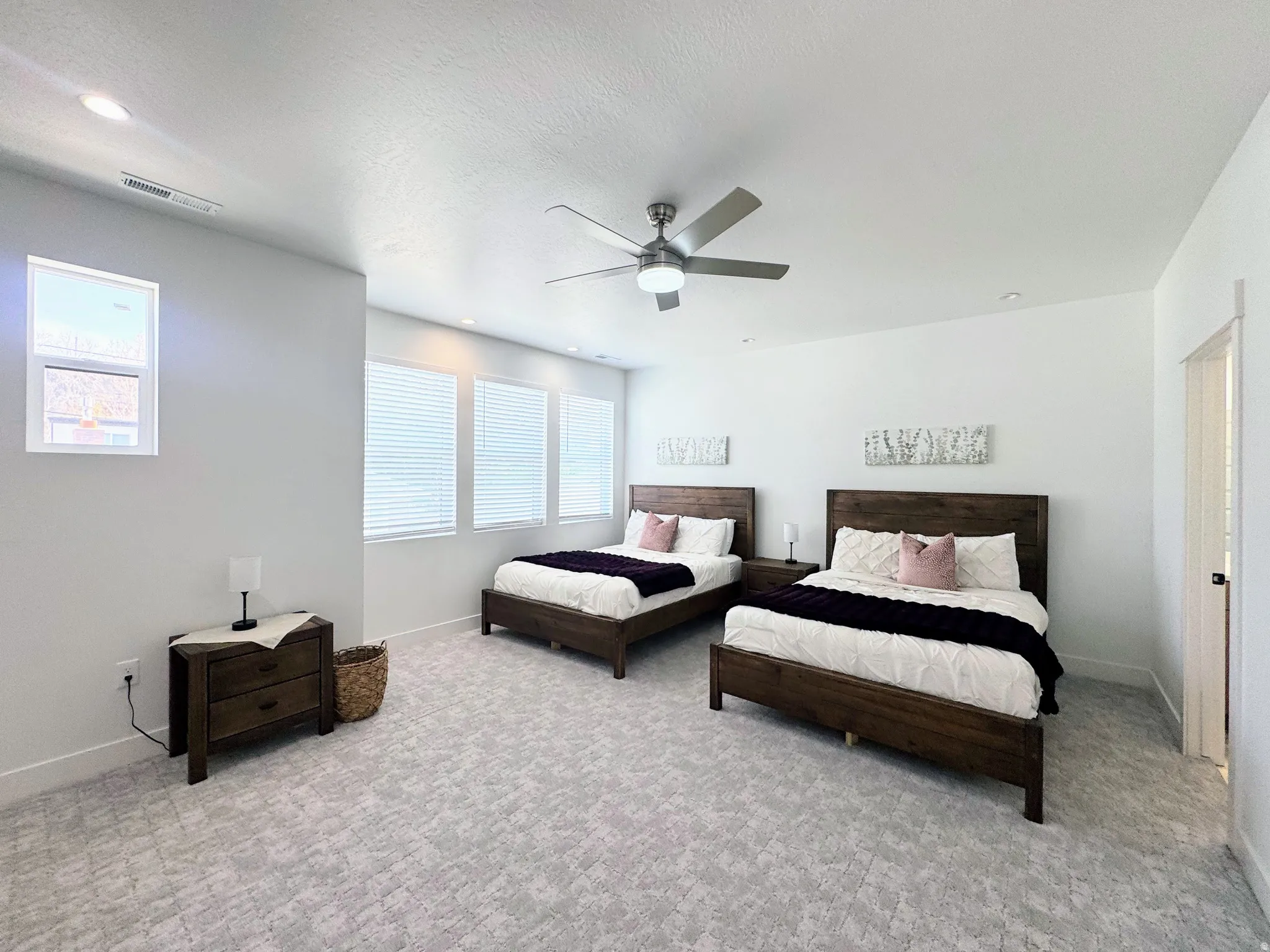 Spacious room featuring patterned carpet flooring, multiple windows with horizontal blinds, and a contemporary ceiling fan with integrated lighting