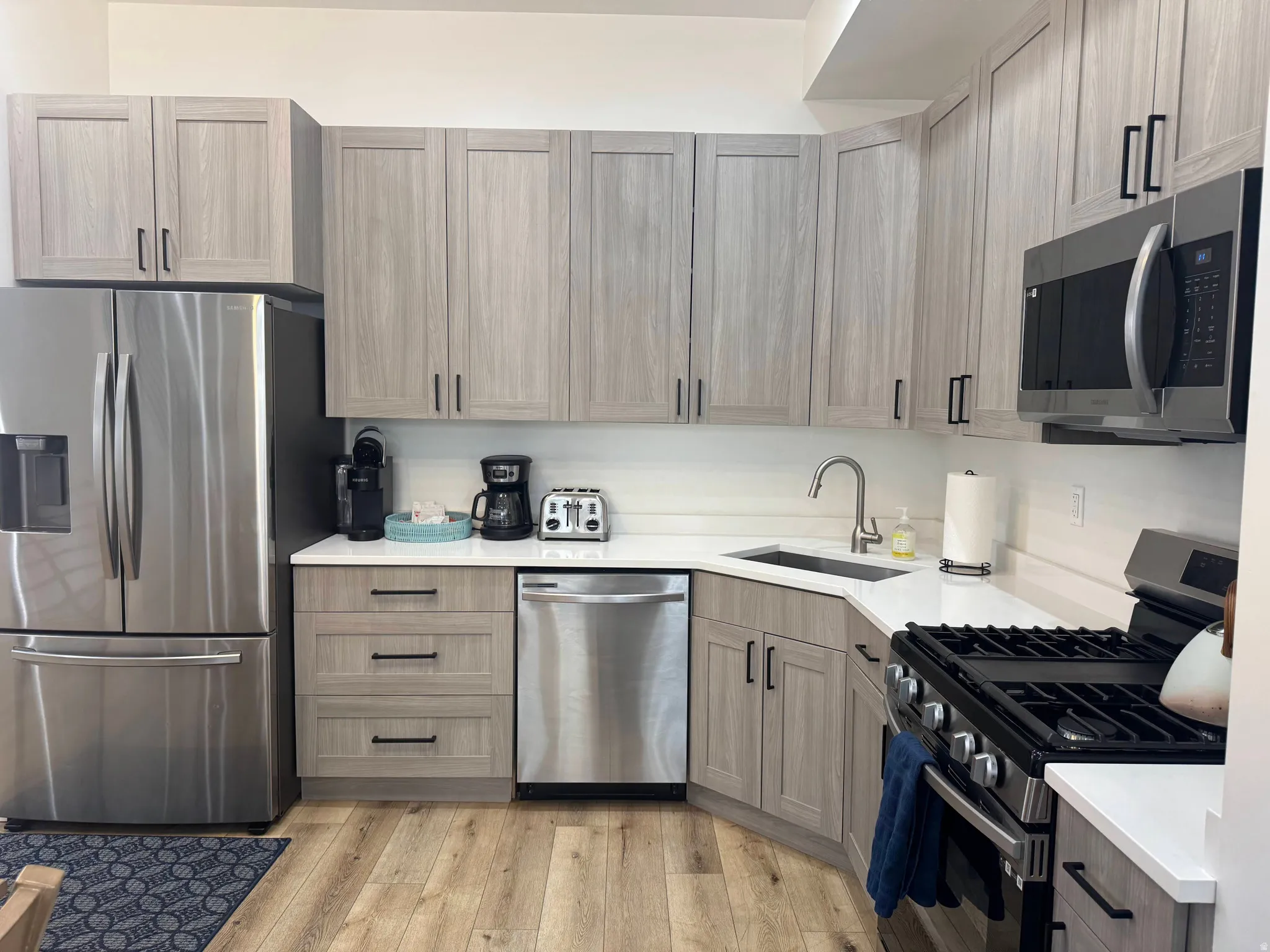 Kitchen featuring wood-finish flooring and light wood-grain cabinetry with dark hardware