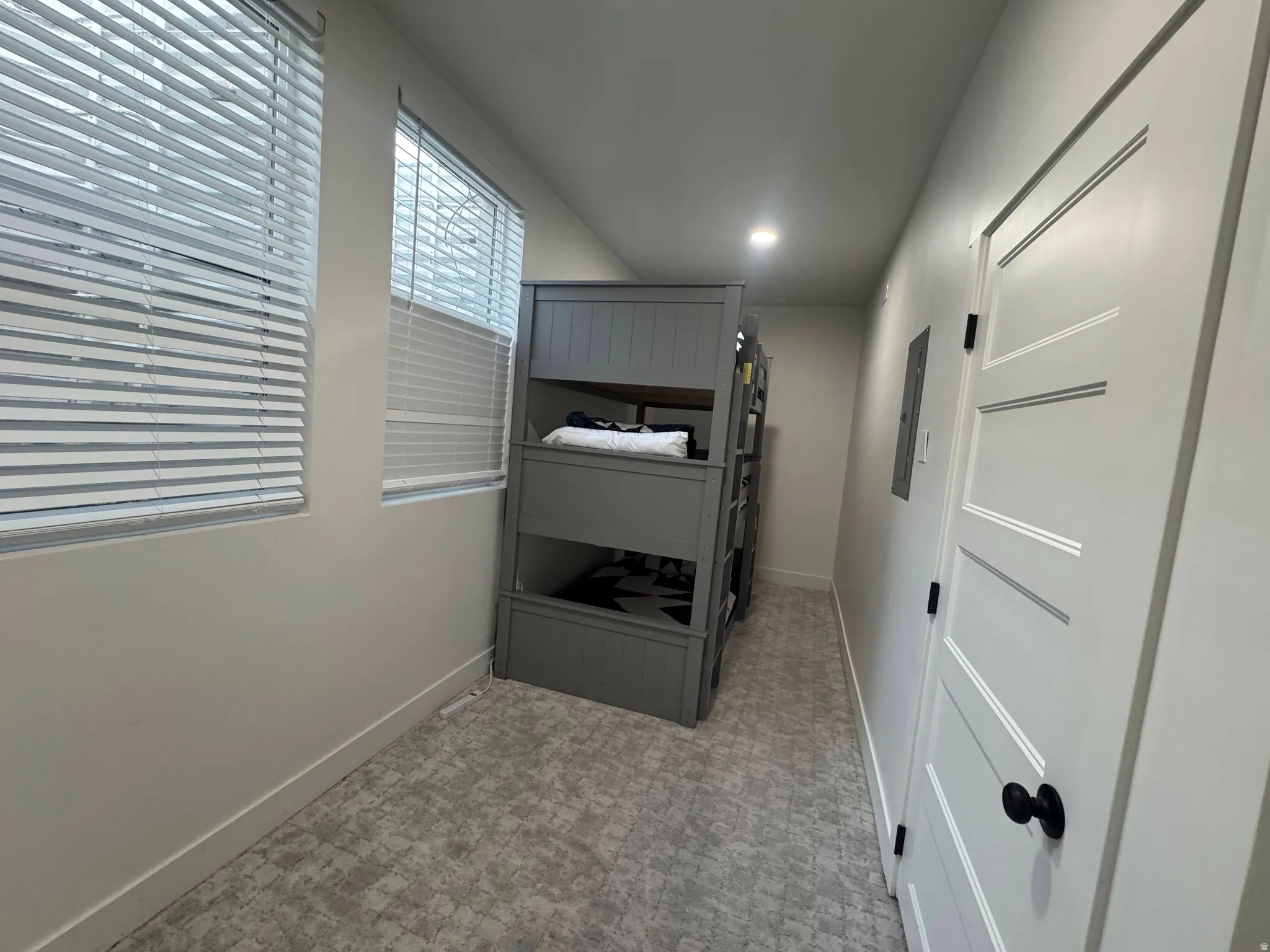Alcove featuring two windows with horizontal blinds, light-toned patterned carpet, a built-in bunk bed structure, a white paneled interior door with a black knob, and recessed ceiling lighting