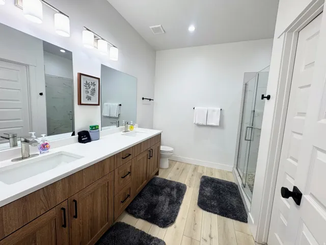 Bathroom featuring a double vanity with wood-finish cabinetry, white countertops, and dual undermount sinks