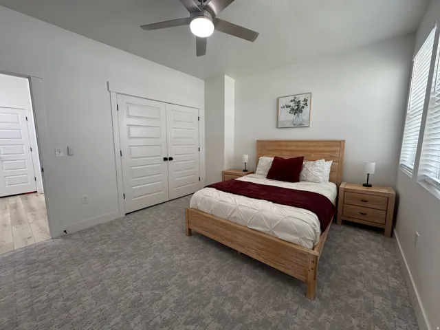 Spacious room featuring broadloom carpeting, a multi-pane window with blinds, and a ceiling fan with integrated lighting