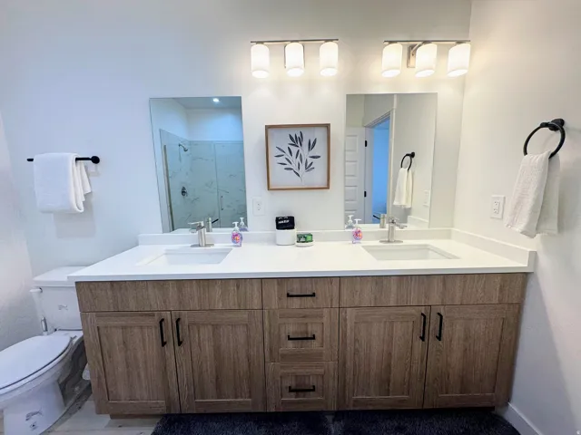 Dual vanity with wood-finish cabinetry, white countertops, and undermount sinks