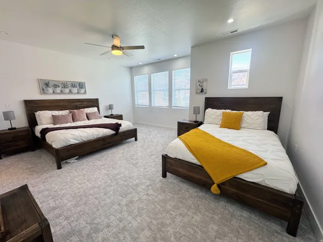 Spacious room featuring patterned carpet flooring, multiple windows with blinds, a ceiling fan with integrated lighting, and recessed lighting