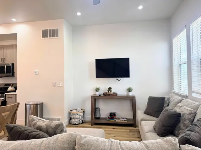 Living area featuring wood-finish flooring, recessed lighting, and large windows with blinds
