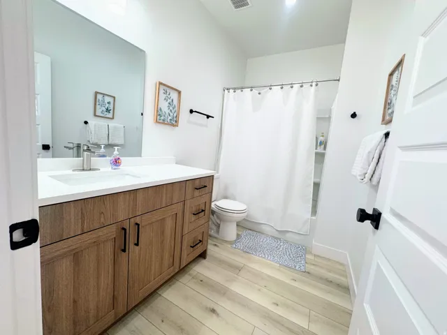 Bathroom featuring a wood-finish vanity with a light-colored countertop, integrated sink, and black hardware