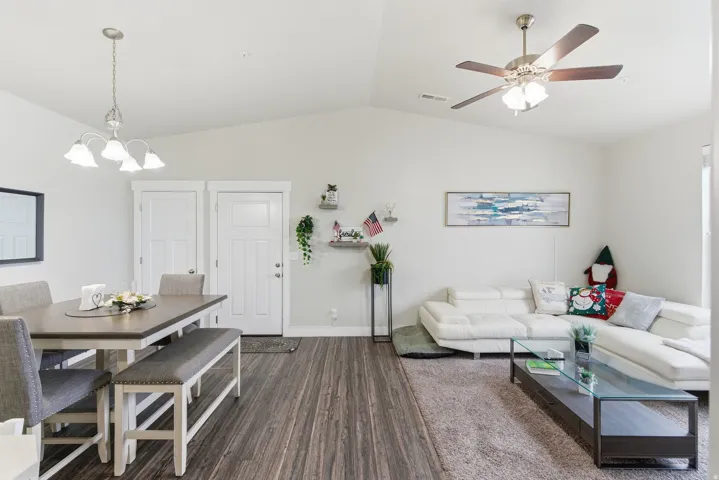 Open-concept living space featuring vaulted ceilings, wood-finish flooring, and ample natural light