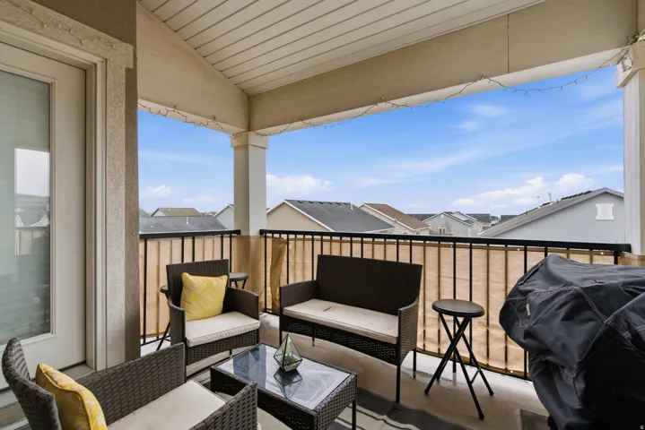 Covered balcony featuring a white railing, a beige privacy screen, and an exterior door with a glass panel