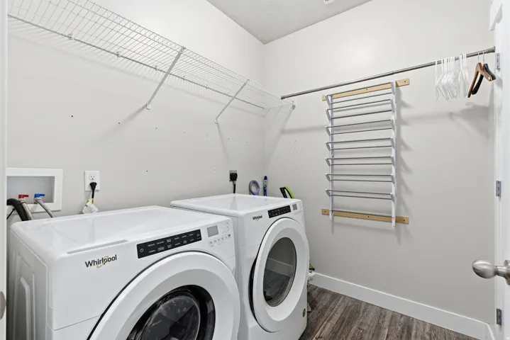 Laundry area featuring wood-finish flooring, white baseboards, and wire shelving