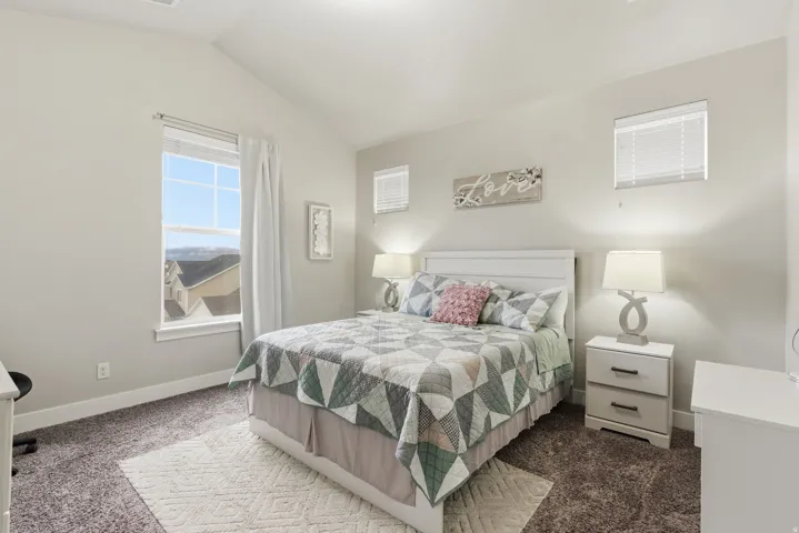 Carpeted bedroom with vaulted ceiling and light-toned walls