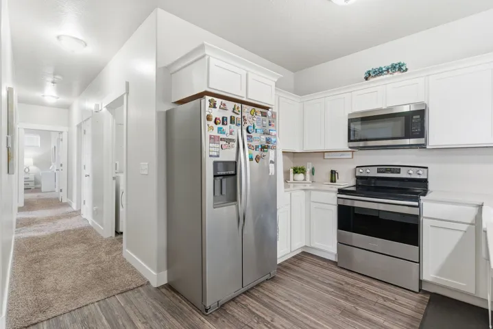 Modern kitchen featuring white shaker cabinetry, stainless steel appliances including a side-by-side refrigerator, and stone-finish countertops