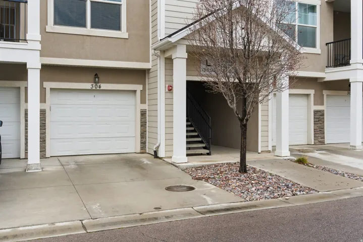 Exterior facade featuring textured stucco, stone veneer accents, and multiple garage doors