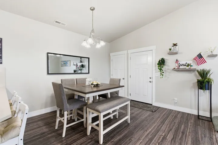 Dining area featuring wood-finish flooring, a contemporary chandelier, white trim, and light-toned walls