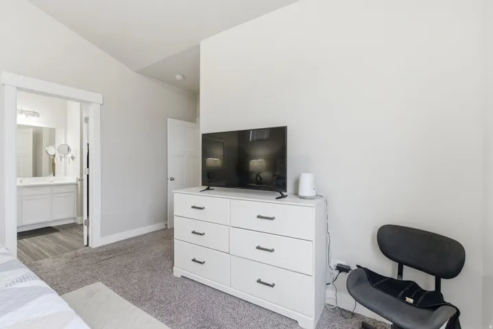 Carpeted room with a vaulted ceiling and light gray walls