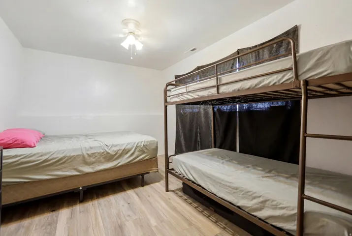 Room with light wood-finish flooring, white walls, and a ceiling fan with integrated lighting
