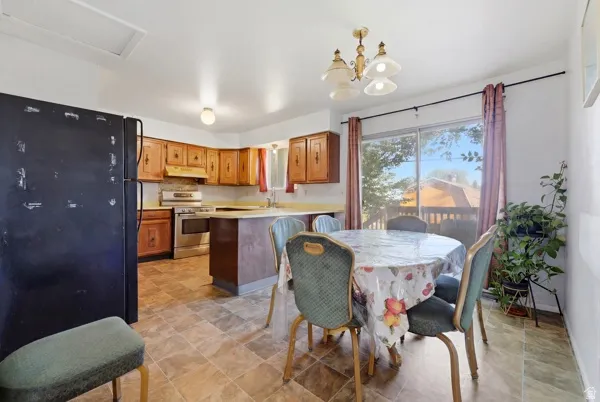 Spacious kitchen and dining area featuring wood cabinetry, stainless steel range, and a breakfast bar