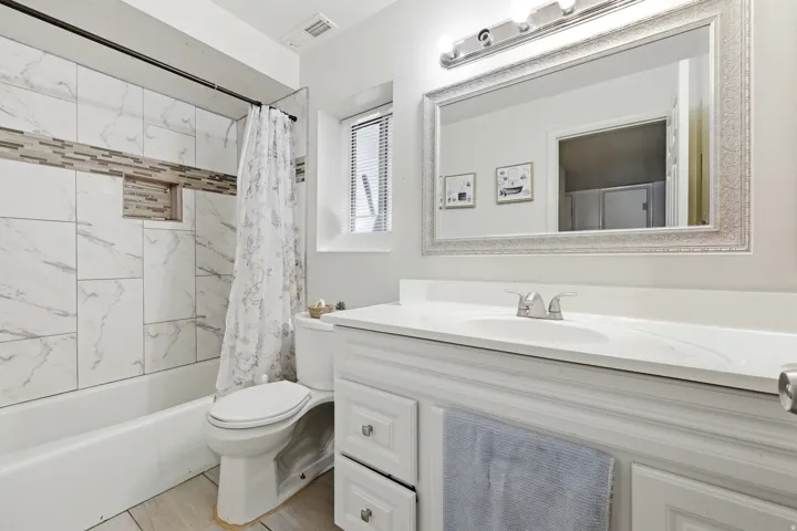 Bathroom featuring a white bathtub with subway tile surround, mosaic accent tile, and a recessed shower niche