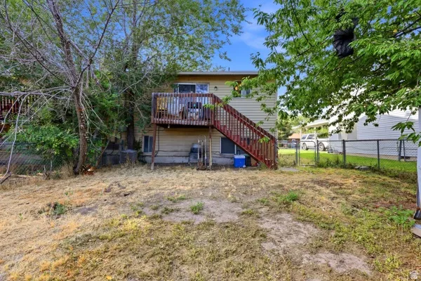 Rear exterior featuring a wood deck with stairs, siding, and a fenced perimeter