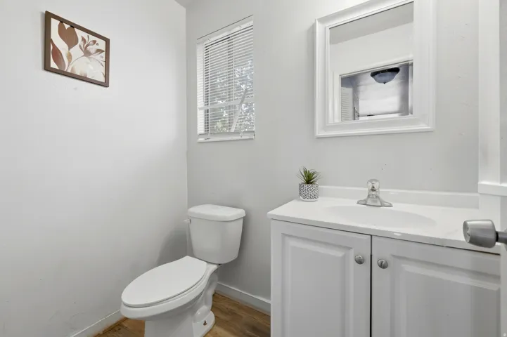 Vanity with integrated sink, white cabinetry, and a framed mirror