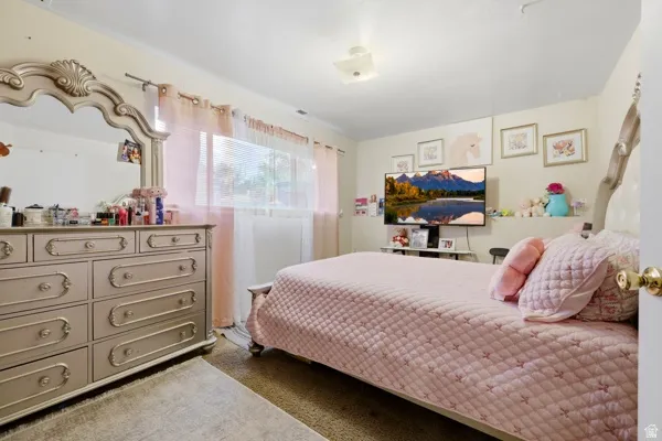 Bedroom featuring a window with blinds, wall-mounted television, and flush-mount ceiling light fixture