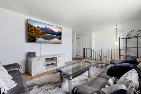Spacious living area featuring light-toned carpeting and a modern entertainment console