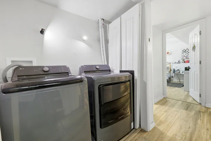 Dedicated laundry area featuring a washer and dryer, light wood-finish flooring, and white paneled doors