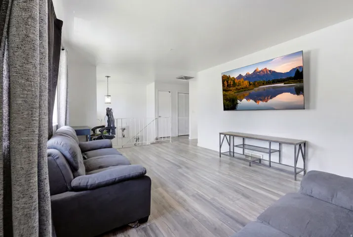 Open living area featuring light wood-finish flooring and white painted walls