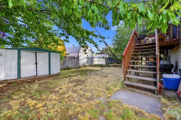 Outdoor space featuring a metal storage shed with double doors, wood fencing, and a multi-level wood deck with stairs