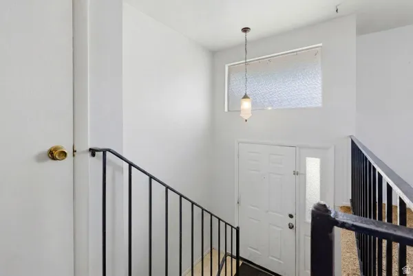 Entryway featuring a decorative pendant light, textured glass transom window, and a multi-panel door with an accompanying sidelight