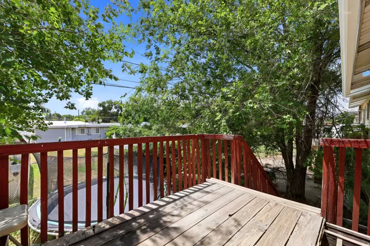 Outdoor wood deck featuring a red railing and steps down to the yard