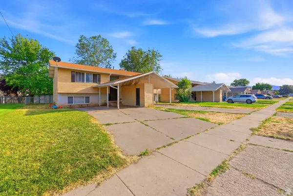 Two-story exterior with light-colored siding, a covered carport, and a concrete driveway