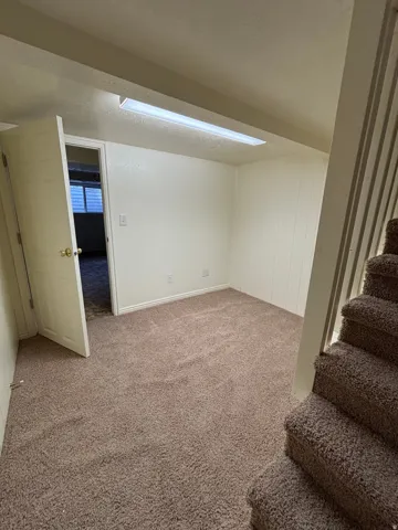Carpeted room featuring a fluorescent ceiling light fixture, white baseboards, and a paneled accent wall