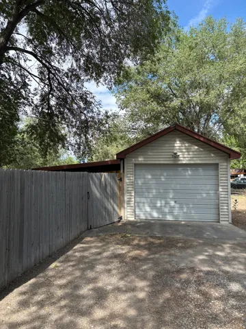 Detached garage featuring horizontal siding, a pitched roof with brown trim, and a roll-up door