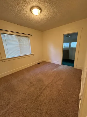 Carpeted interior space featuring a single window with blinds and white trim
