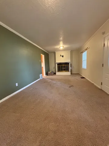 Spacious interior room featuring a central fireplace with a brass firebox, crown molding, and two-tone wall paint