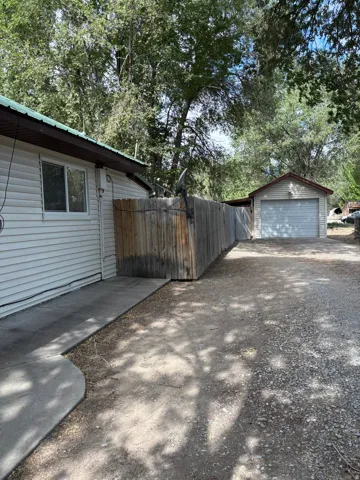 Detached garage with a paneled door, wood siding, and gabled roof
