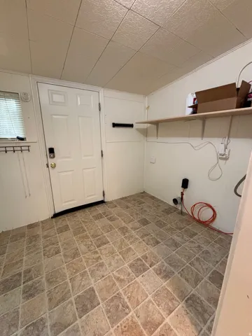 Utility space featuring patterned square tile flooring, white paneling, and a white paneled door