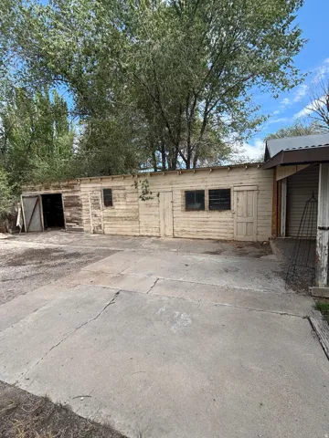 Outbuilding with wood siding and various access points, featuring a concrete pad