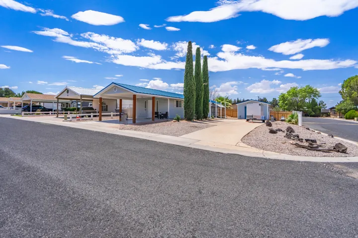 Property exterior featuring a blue metal roof, covered carport, and a gravel front yard