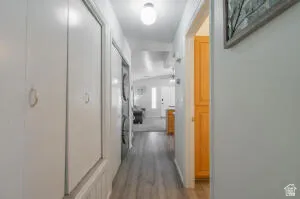 Hallway featuring wood-finish flooring, white wall paneling, built-in storage cabinetry, and a stacked washer and dryer unit