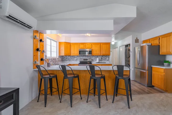 Kitchen featuring light wood cabinetry, stainless steel appliances, and a mosaic tile backsplash